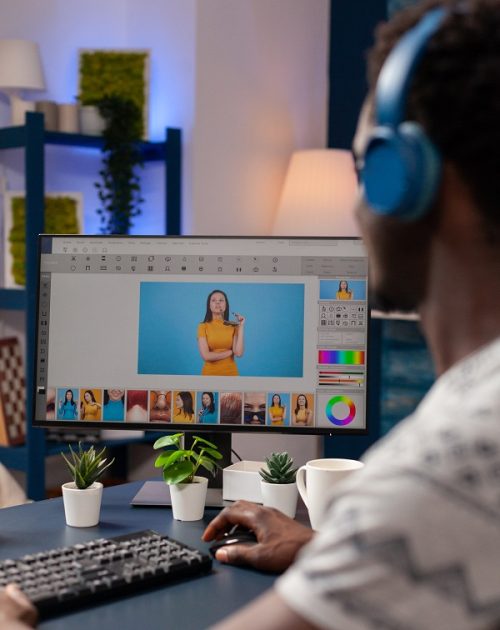 African american artist photographer with headset retouching designer pictures using digital post production software. Young illustrator editor editing creative photography working remote from home